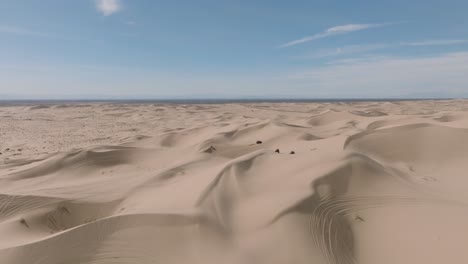 無人機拍攝在陽光明<unk>的沙丘上,atv沙丘小車穿過山峰