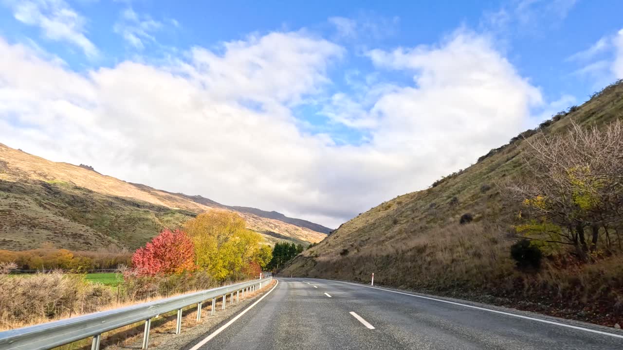A serene drive through Wanaka's stunning landscapes, featuring winding roads, lush greenery, and expansive skies under soft daylight