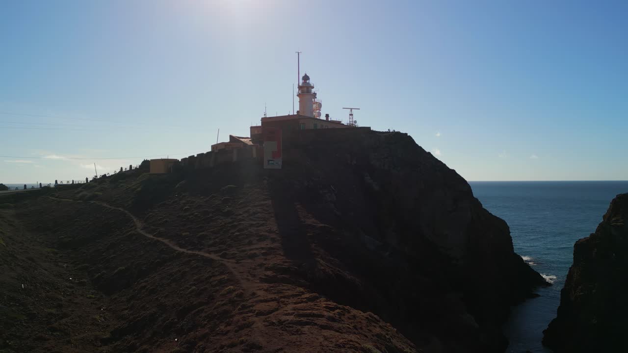 Faro su una scogliera rocciosa che si affaccia sull'oceano in una giornata di sole