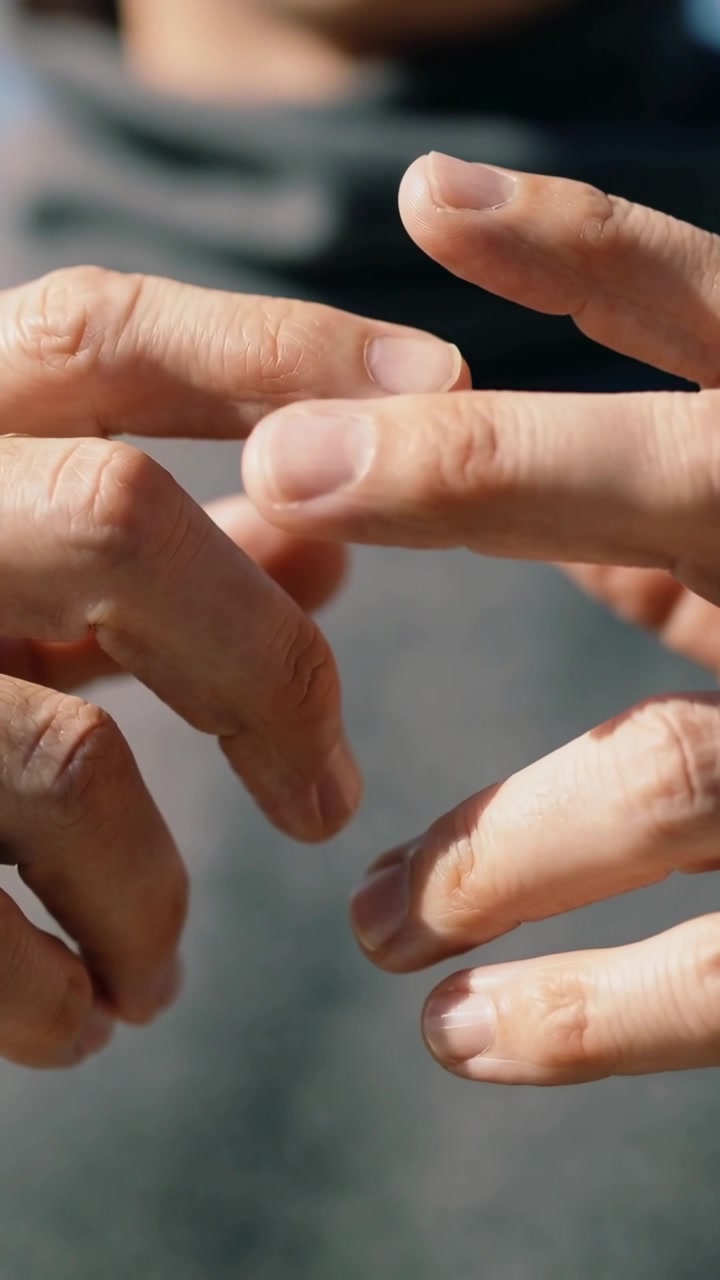 Adult man moving fingers, bringing fingertips together after holding hands apart in sunlight
