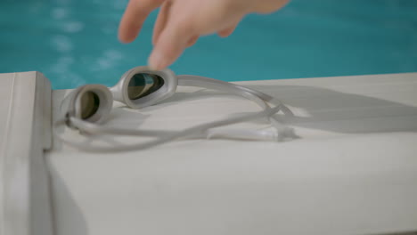 La-Mano-Recoge-Las-Gafas-Junto-A-La-Piscina