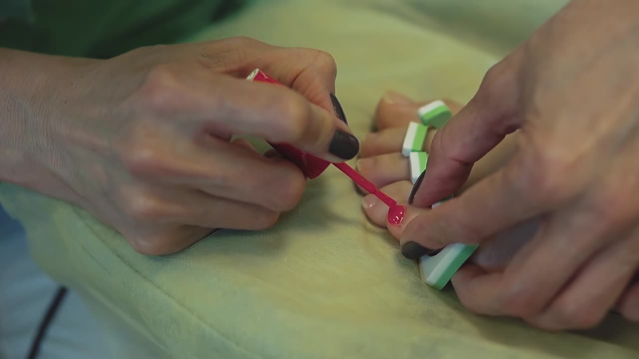 pediculista de primer plano pinta las uñas de los pies de una mujer joven 1