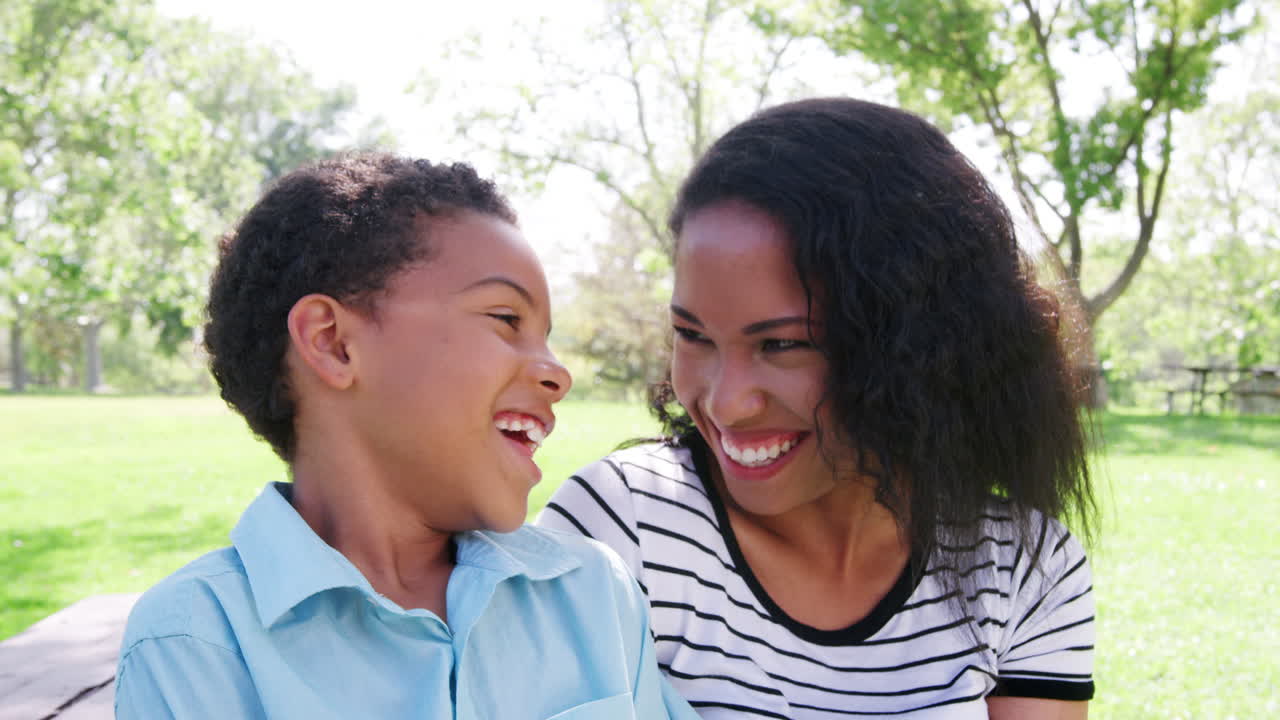 Slow Motion Portrait Of Smiling Mother With Son Relaxing In Park