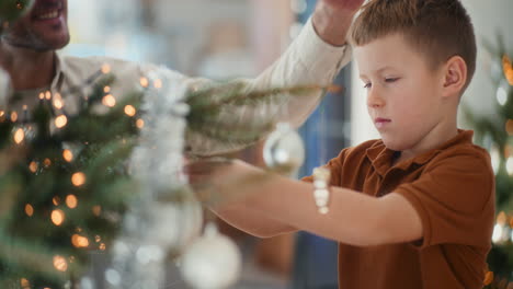 young boy decorates the christmas tree with dedication