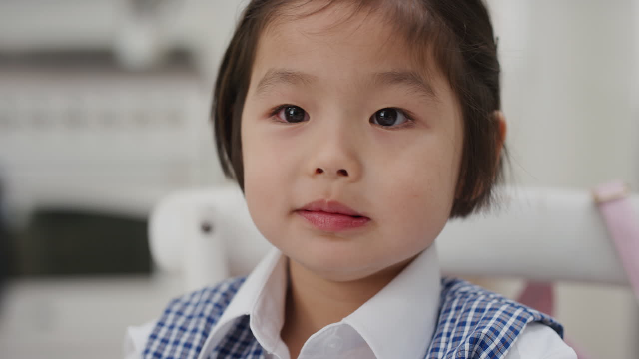 可愛い小さなアジアの女の子が朝食を食べ ⁇ キッチンでシリアルを楽しんで ⁇ 学校の制服を着て準備をしています ⁇ 4k