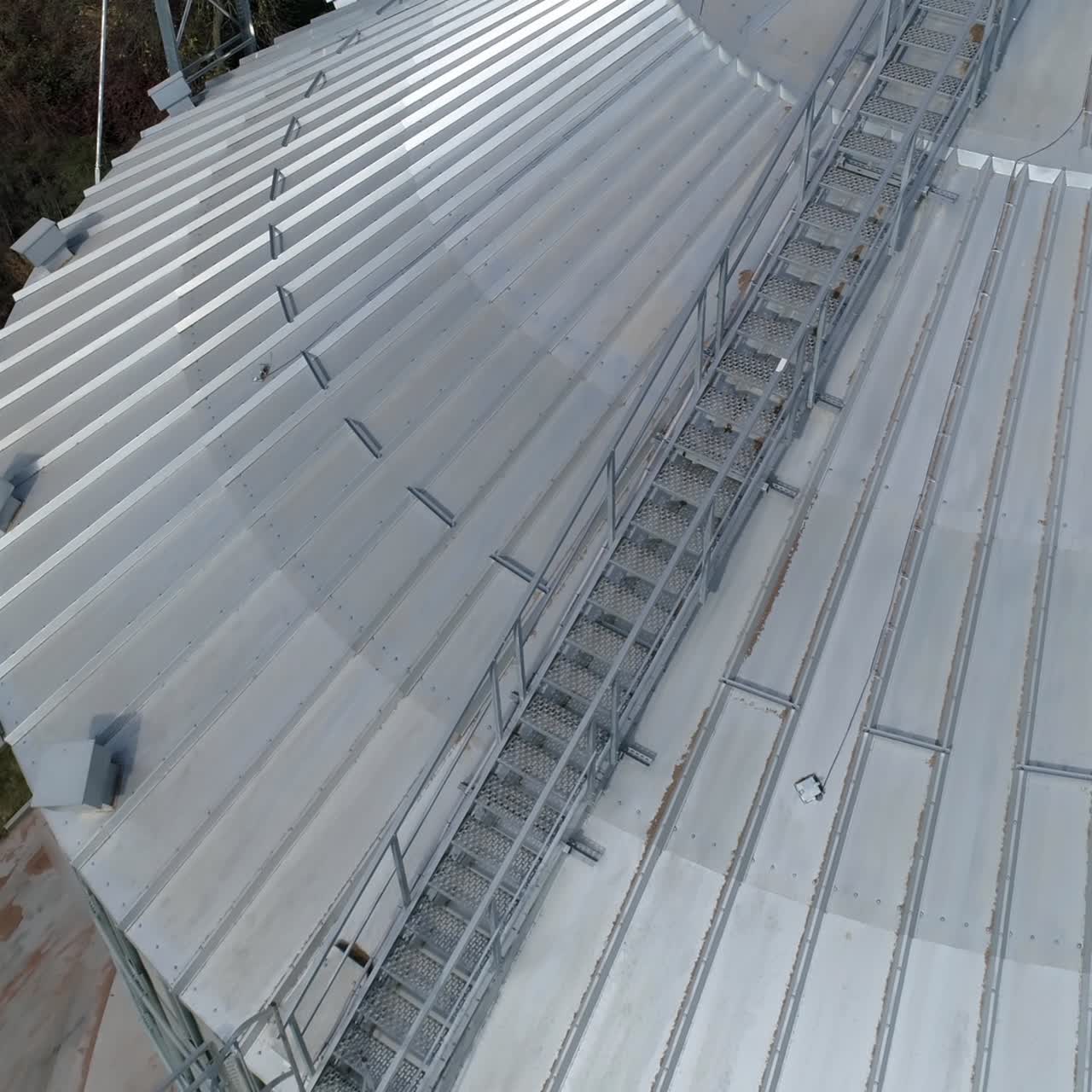 Large grain elevator. Silver granary from above. Aluminum container. Agricultural equipment for storing crop. Top aerial view