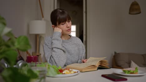 woman reading a book during breakfast