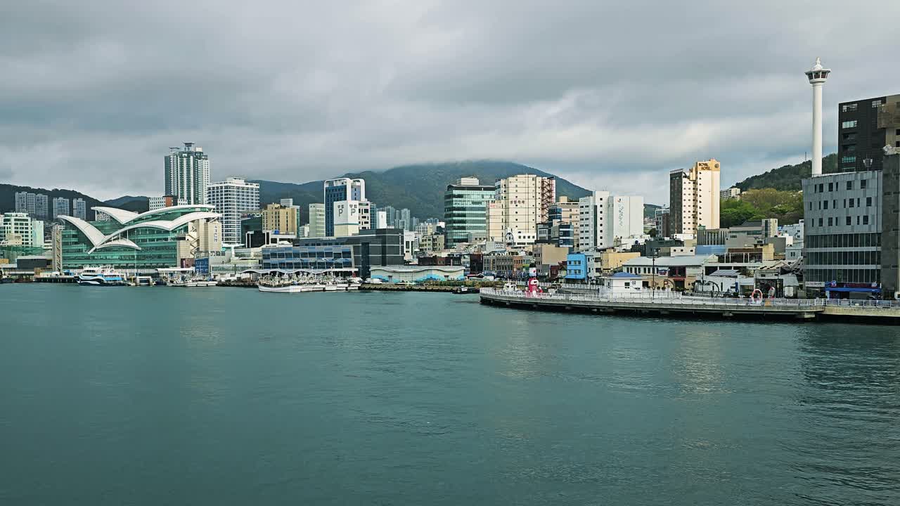 Busan Tower rises above Jung District’s skyline and waterfront in Busan, South Korea, with city buildings and harbor