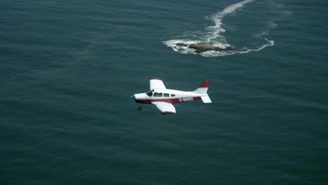 avión privado de un solo motor que vuela sobre el mar, vista aire-aire
