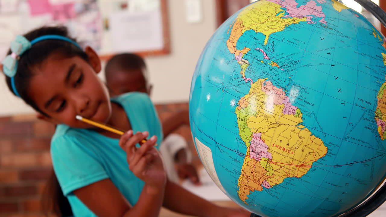 niña mirando el globo y escribiendo en el aula