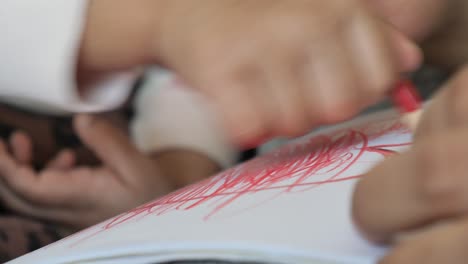 child drawing with red crayon