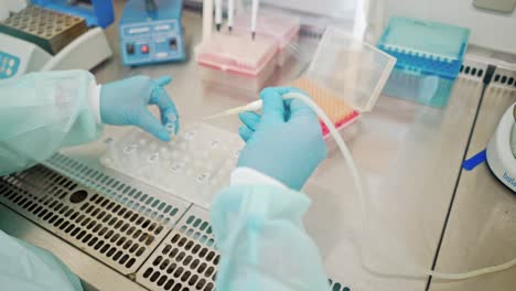laboratory assistant working with test tubes. female hands in protective gloves filling vials with liquid by a special plastic tube in the laboratory.