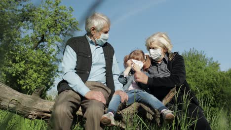 grandparents with granddaughter in medical masks in park. coronavirus quarantine