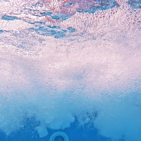 Bubbles rising to the surface. Air bubbles in clear blue water in pool. Many bubbles in the water of the swimming pool. Close-up.