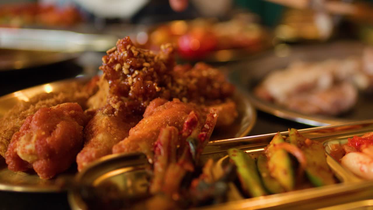 Hands use scissors to cut grilled meat, surrounded by Korean dishes, warm indoor lighting, close-up
