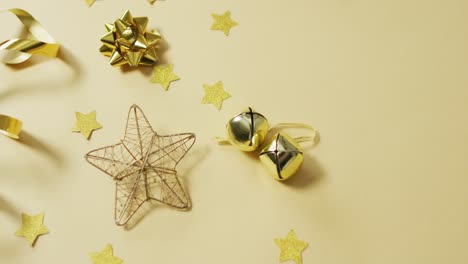 Video-of-gold-christmas-decorations-with-stars-on-yellow-background