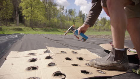 agriculture - farmer uses blow torch to mark divisions for planting garlic