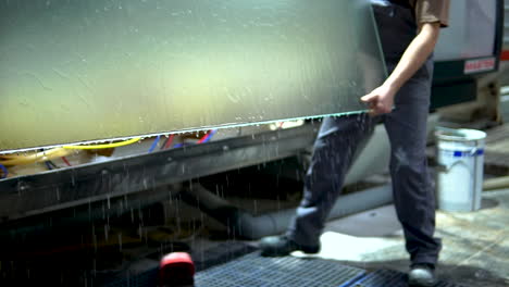 workers shifting large sheets of glass from washer machine to the next processing unit at glass manufacturing industry