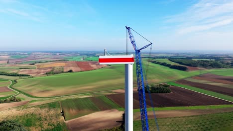 tower and nacelle of wind turbine under construction with a crane at wind farm