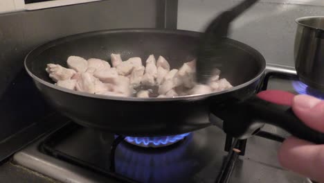 persona friendo carne de pollo en estufa de gas