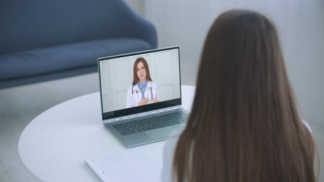 Shoulder-view-young-woman-consulting-with-family-therapist-doctor-general-practitioner-online-via-video-call-on-laptop-after-feeling-first-virus-illness-symptoms-medical-insurance-covid19-outspread.
