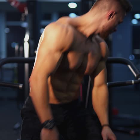 sportsman on a simulator. handsome guy without shirt with muscular body exercising in modern sports center. portrait of concentrated bodybuilder at gym