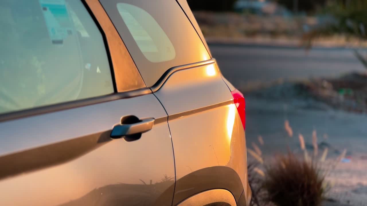 4K close-up of a car door glowing with warm sunset reflections. A cinematic automotive beauty shot ideal for luxury, travel, commercial, and nature contrast themes.