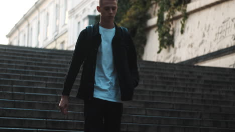 Young-student-walking-down-stairs-outdoors.