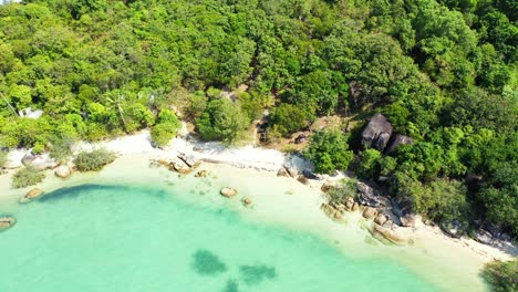 beautiful-tropical-island-with-white-sand-beach-and-palm-forest,-surrounded-by-crystal-clear-turquoise-water-of-the-sea-with-corals-on-the-seafloor