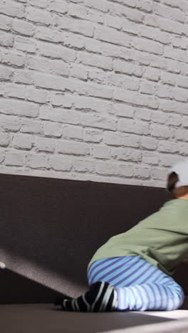 happy energetic toddler boy jumping on the sofa. funny kid having fun playing at home. vertical video