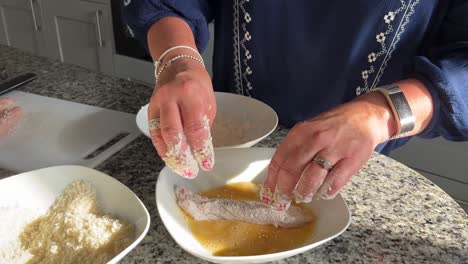 young lady preparing chicken in a large and expensive kitchen making a famous dish named kats curry