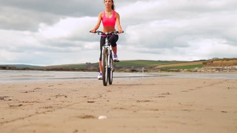 Fitte-Brünette-Beim-Radfahren-Am-Strand