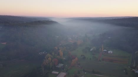early morning fog and smoke from bushfires covering houses in countryside western australia at sunrise