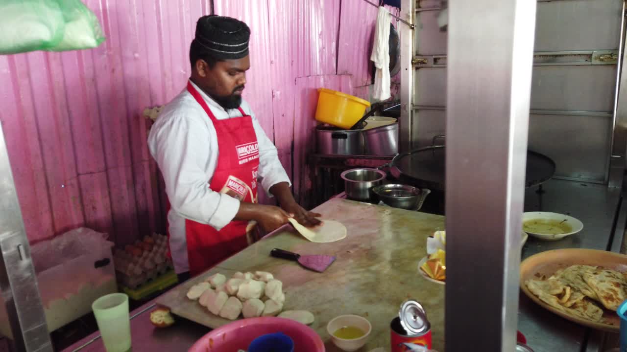 Indian man making roti canai (Indian-influenced flatbread dish), popular dish in southeast asia