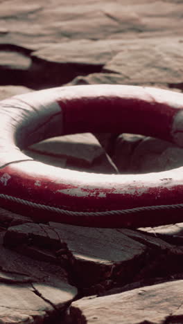 close up of a red life preserver on a rocky beach