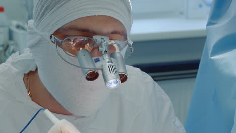 cirujano con herramienta óptica trabaja en la clínica. médico cardiólogo con máscara de gasa utiliza bisturí láser para cirugía de derivación de la arteria coronaria en el hospital