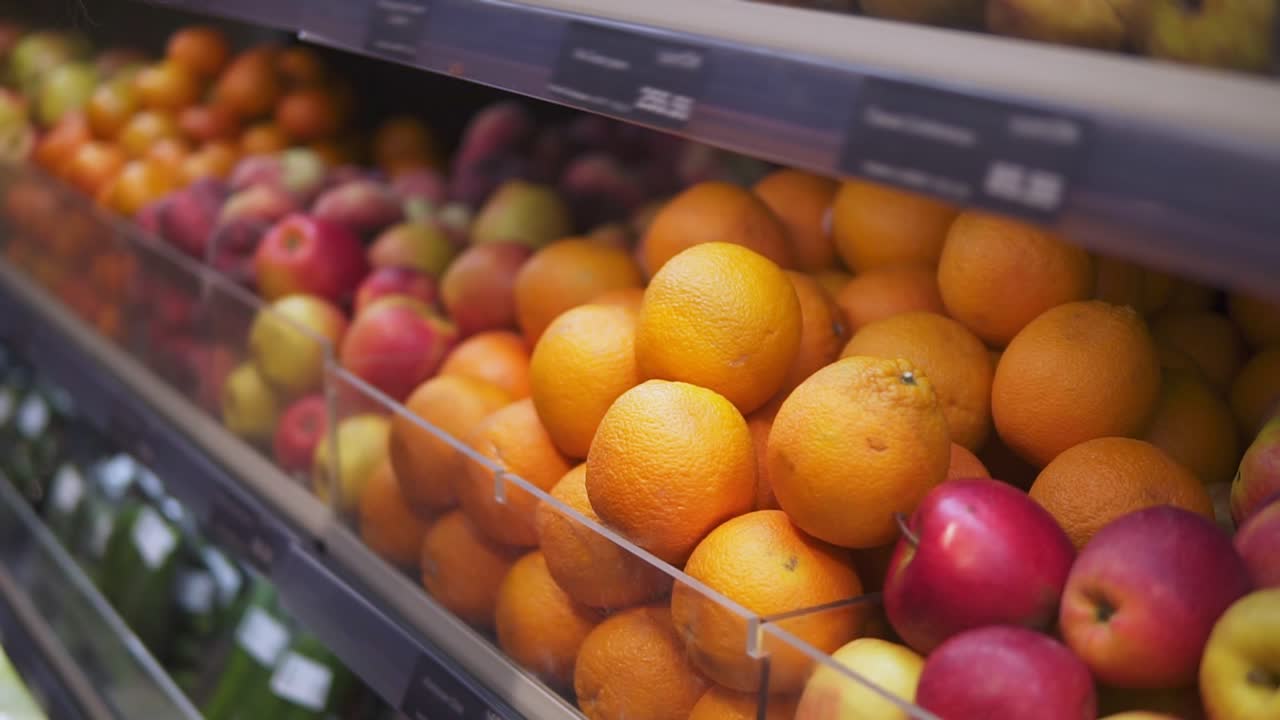 Man's hand selecting fresh fruits in grocery store produce department from shelf. Young guy is choosing oranges in supermarket. Side view. Close up