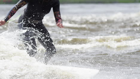 woman athlete - surfing on a river wave