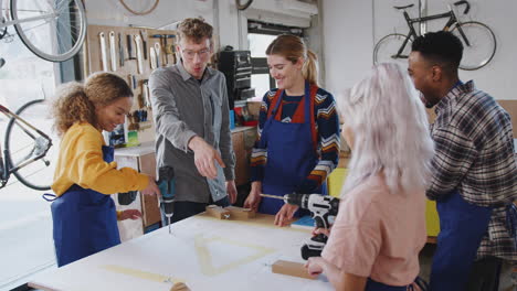 Multi-Cultural-Team-Of-Trainees-In-Workshop-Learn-How-To-Assemble-Hand-Built-Bicycle-Frame-Together