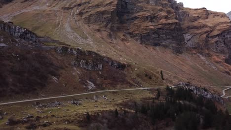 aerial shot of car driving in the distance on a road through rocky mountain landscape