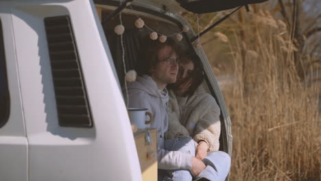 a young couple in love in the back of a caravan by a lake