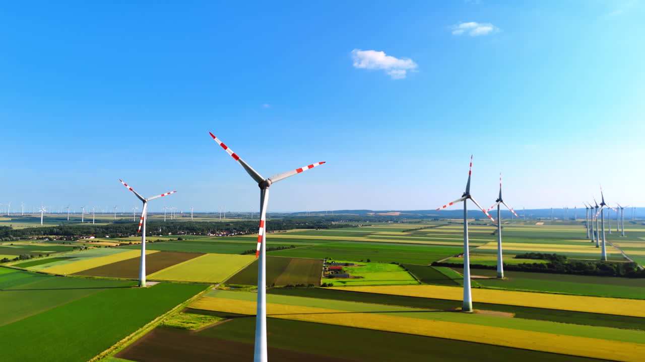 Vast agricultural plantations with wind farms. Beautiful blue sky with tiny clouds at backdrop. Aerial view.