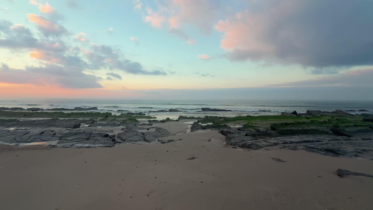caminando hacia las rocas cubiertas de algas en una playa tranquila durante una tarde perfecta junto al mar