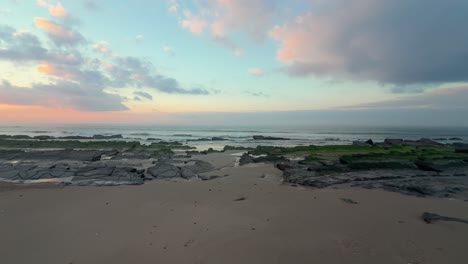 Walking-towards-algae-covered-rocks-on-a-peaceful-beach-during-a-perfect-seaside-afternoon