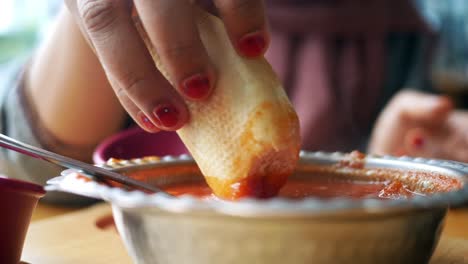 woman dipping bread in tomato sauce