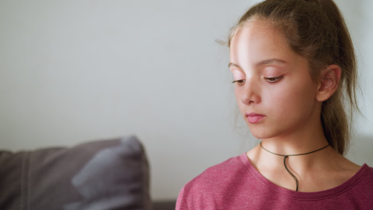 Cute girl with rope around her neck looks calm with her hair tied back, soft light reflects gently on her face while she appears serene, creating a tranquil atmosphere