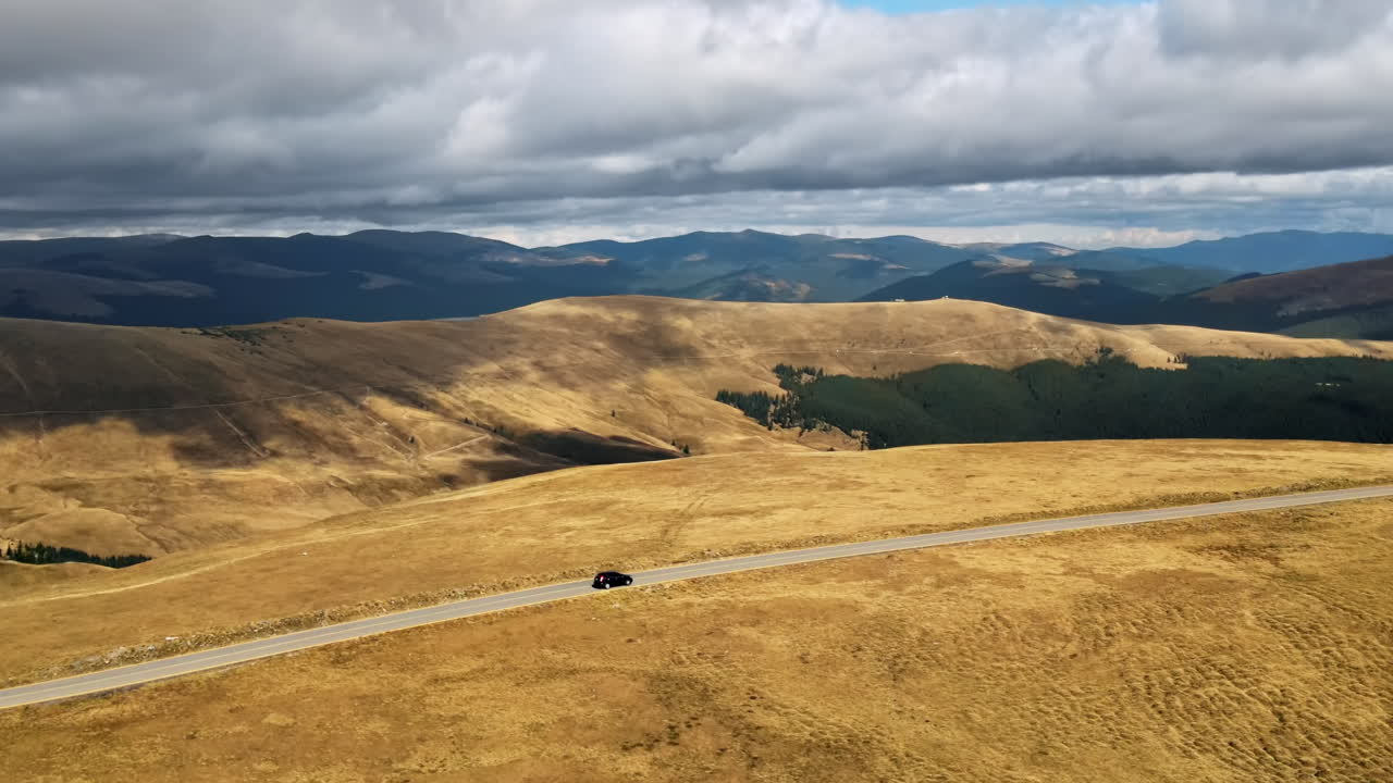 Aerial drone view of nature in Romania. Carpathian mountains, sparse vegetation, Transalpina road with car
