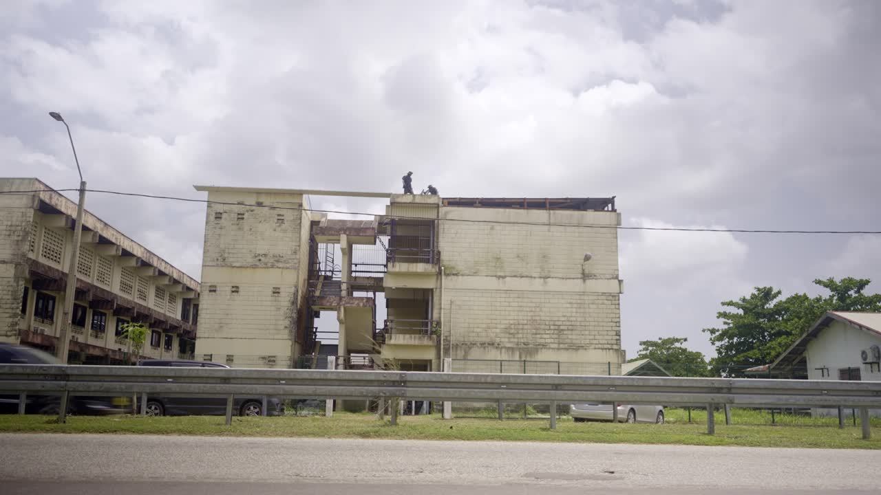 View from the street of Natin school building in Paramaribo Suriname, cars driving by