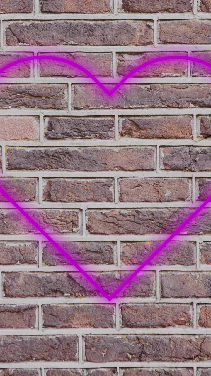 Insegna al neon a forma di cuore su muro di mattoni 4k