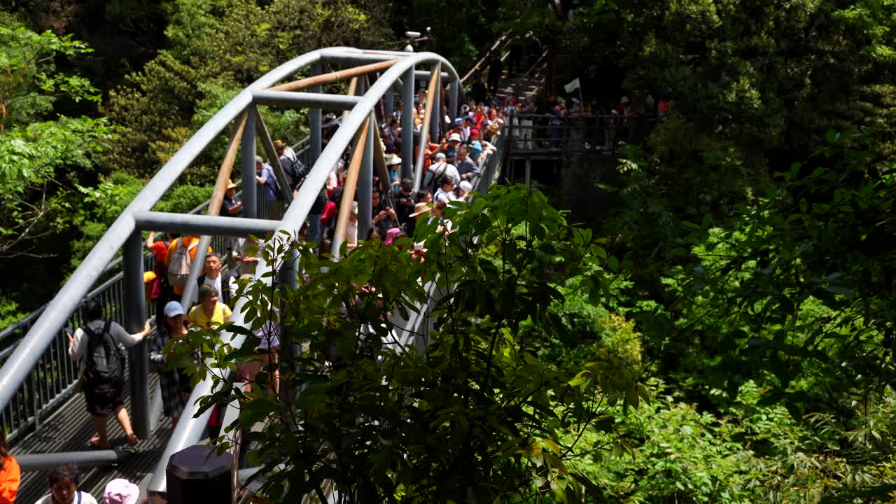People gathered on the edge of a bridge in Yuanjiajie. Mass tourism scene in Zhangjiajie, China